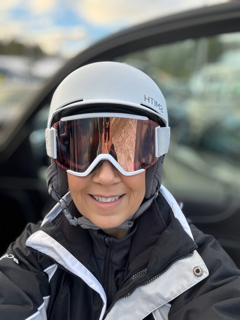 Deb Mitzel with ski helmet and gear, ready to get out there.